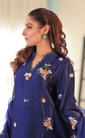 Model wearing cobalt blue Sheesha silk outfit with hand embroidery, scalloped hem, and organza dupatta finished with silk border and gota work