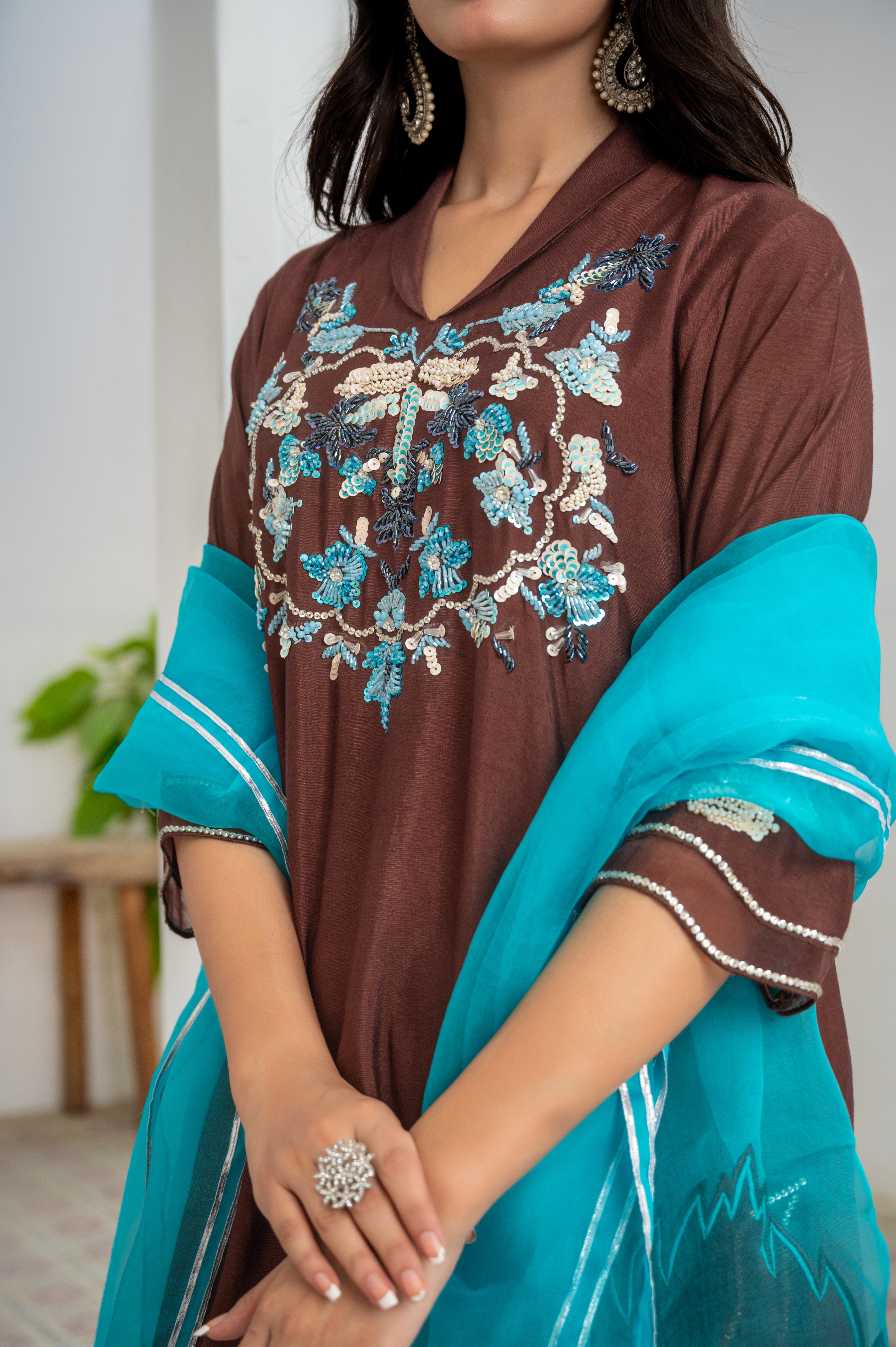 Model wearing Mocha Sea 3-piece khaadi silk outfit in mocha brown with aqua blue hand embroidery, paired with organza dupatta featuring colored pati borders